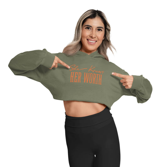 She Knows Her Worth Green Cropped Hoodie For Women front view with woman pointing to slogan.